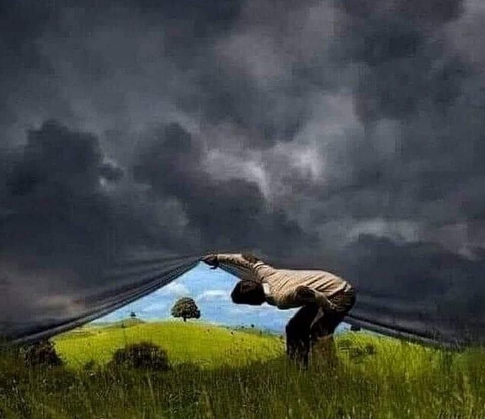 A man lifts what looks like a large canvas or backdrop, revealing a bright, sunny sky behind it, as if he is uncovering a clear day hidden beneath a dull surface.